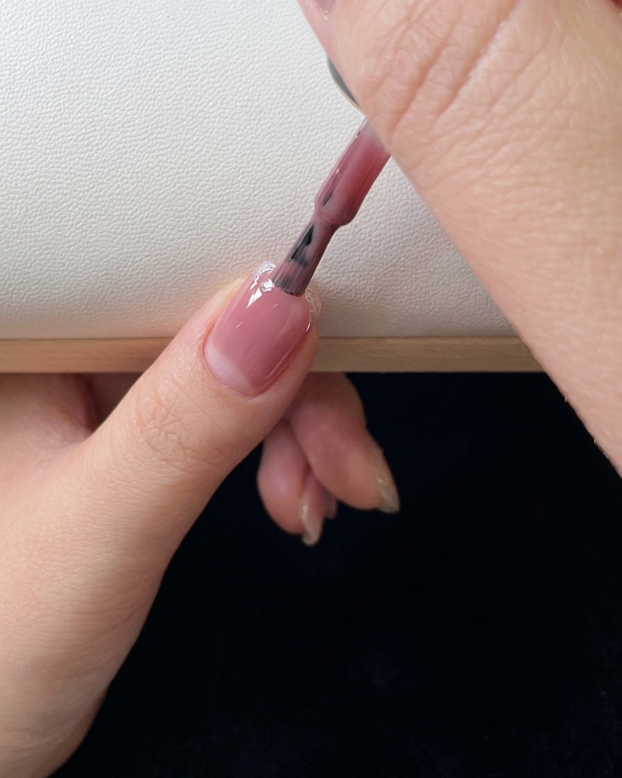 핑크 젤을 두 번째로 바르고 손톱 아래쪽으로 색상을 블렌딩하는 네일 브러시의 클로즈업 사진입니다.