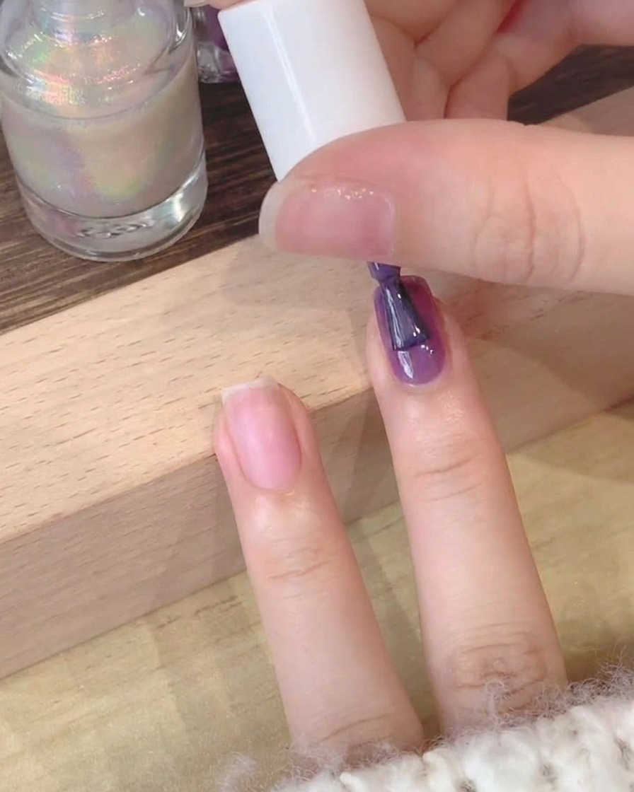 손톱에 딥 퍼플 젤 폴리쉬를 바르는 근접 샷