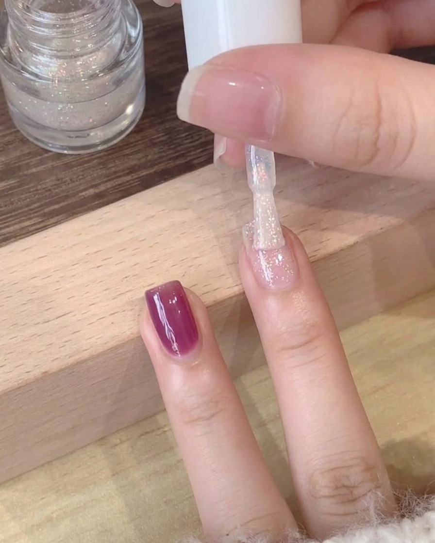퍼플 젤 베이스 위에 쉬머 편광 탑 코트를 바르는 근접 샷