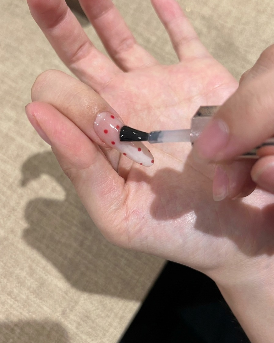 완성된 네일 위에 투명한 탑 젤을 발라 마무리하는 모습.