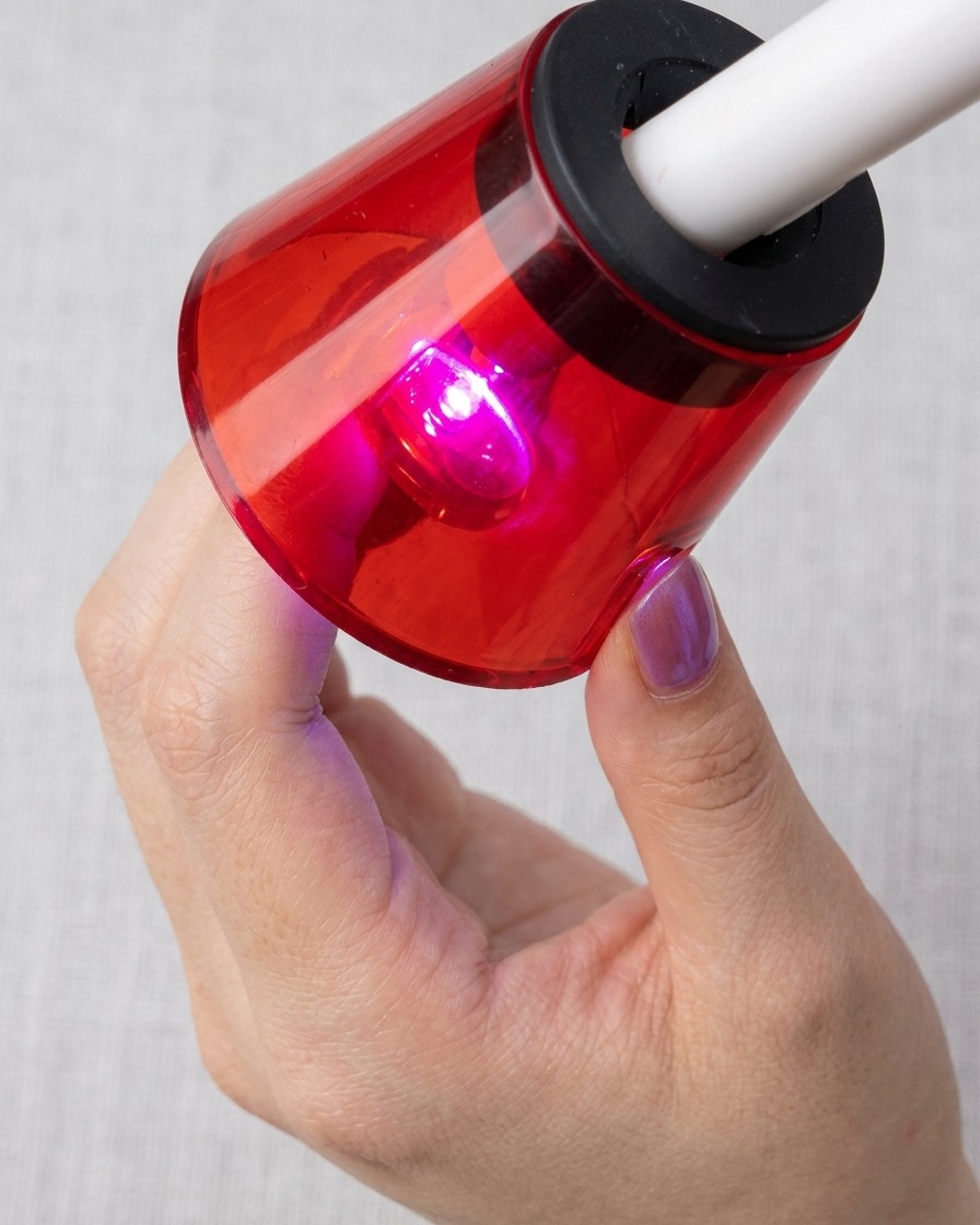 캣츠아이 마그네틱 입자가 선명하게 드러난 네일을 붉은색 UV/LED 램프 아래에서 큐어링하는 모습.