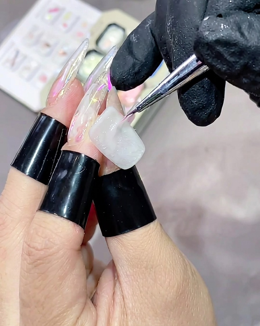 얇은 라이너 브러시로 흰색 베이스를 바른 네일 위에 핑크색 고광택 텍스처 젤을 가로로 길게 바르는 모습.