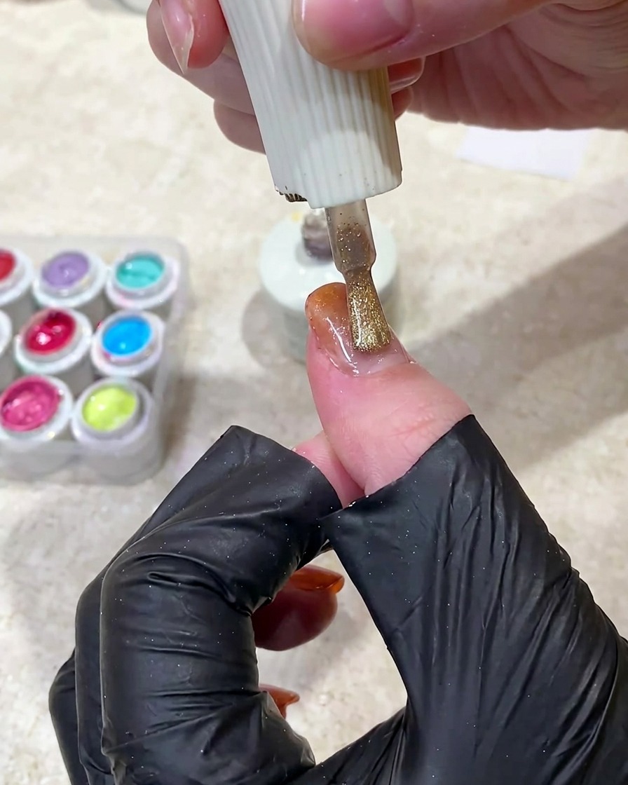 마르지 않은 젤 네일 위에 자석을 대고 자기장 입자를 이동시켜 빛나는 띠를 만드는 모습.