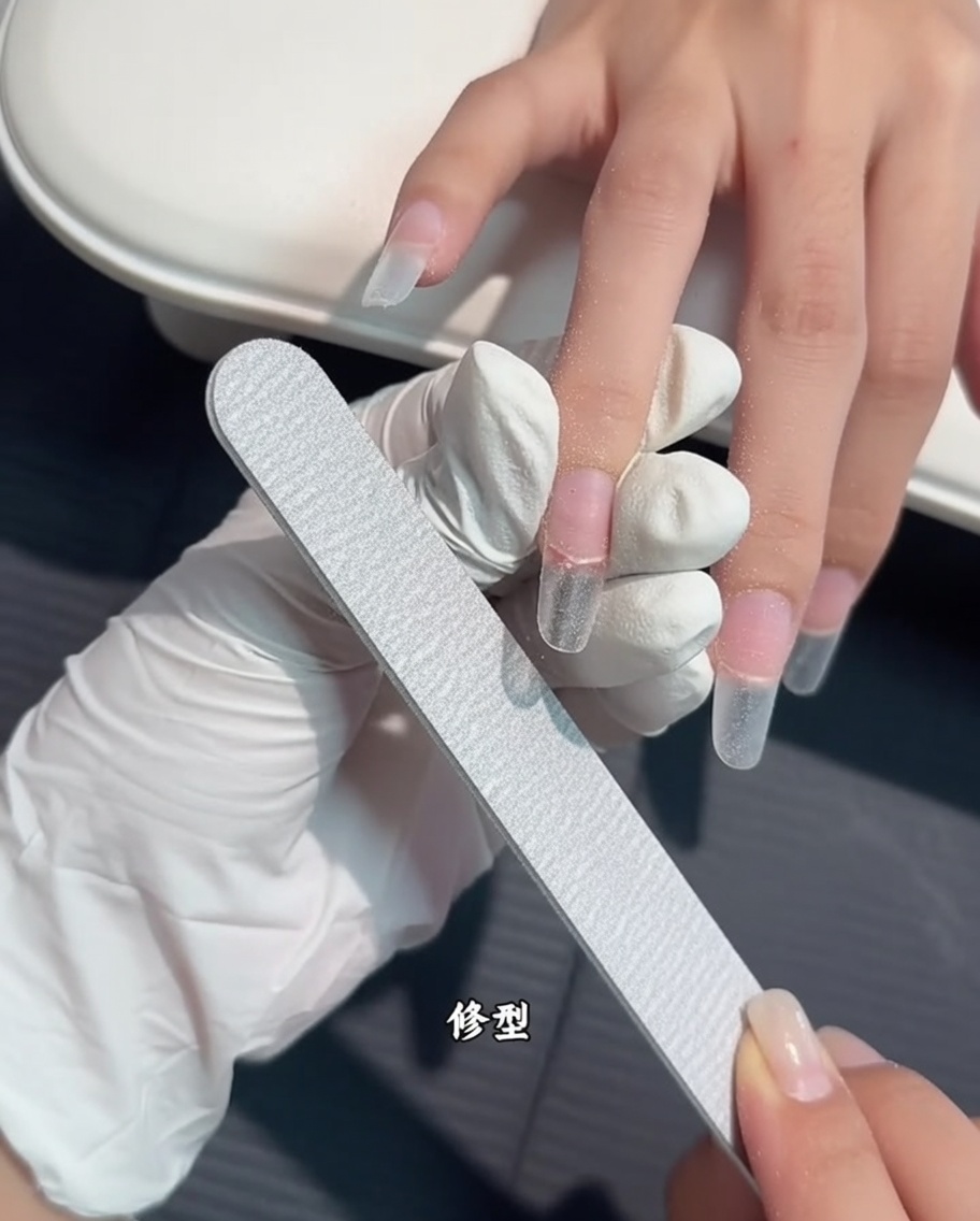네일 파일로 연장팁의 측면과 끝부분을 다듬는 모습.