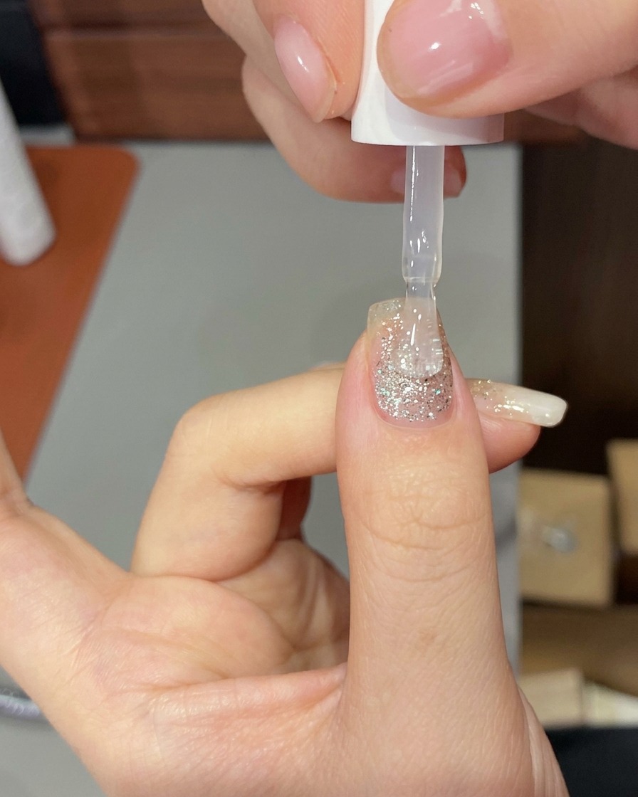 UV/LED 램프 안에서 빌더 젤이 큐어링되며 조명을 받고 있는 손 모습.