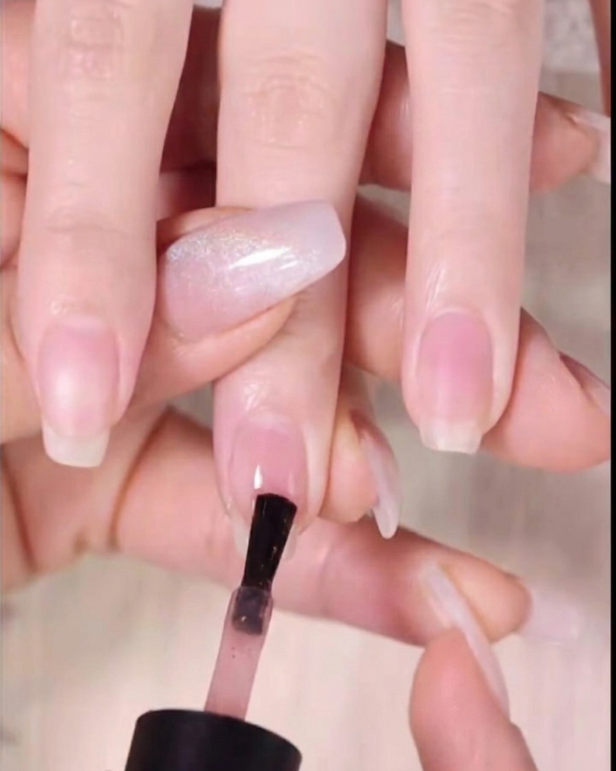 손톱 끝 3분의 1 지점에 짙은 앰버 젤을 바르는 네일 폴리시 브러시.
