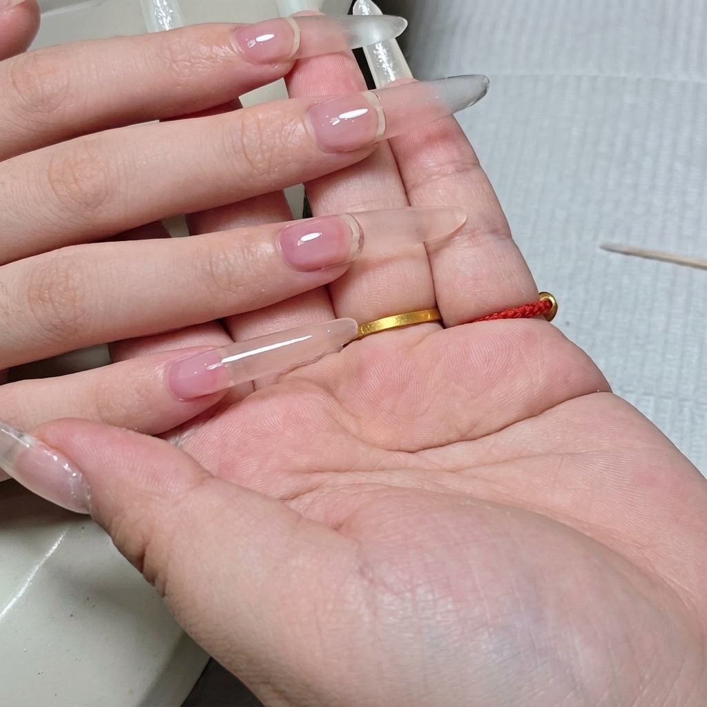 측면에서 본 완성된 투명 연장 손톱의 매끄러운 곡선과 형태.