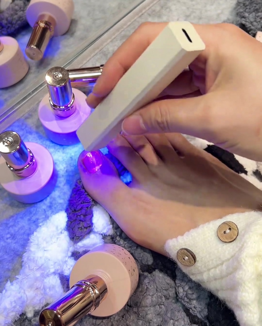 휴대용 UV/LED 램프로 엄지발톱을 굽는 모습.