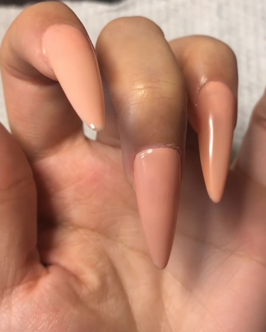 검지 손톱의 누드 젤 위에 탑코트를 얇게 펴 바르는 모습.