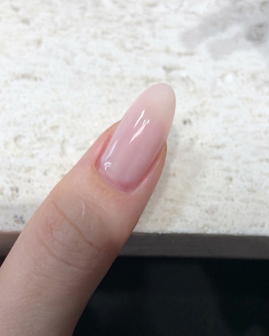 누드 핑크 젤리 폴리시가 매끄럽게 발린 손톱의 근접 모습.