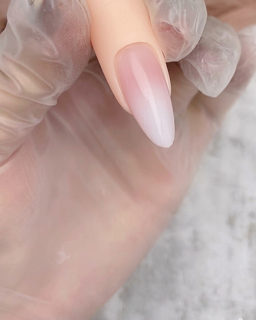 누드 베이스 위에 부드럽고 옅은 화이트 에어브러시 그라데이션이 적용된 아몬드 쉐입 네일 팁.