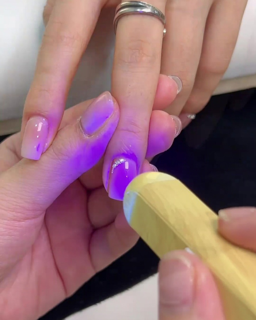 휴대용 미니 UV 램프로 스톤을 큐어링하여 단단히 고정하는 모습.
