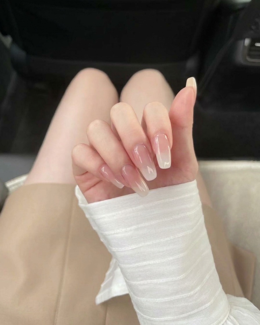 투명한 네일 팁에 클리어 베이스 코트를 바르는 모습.