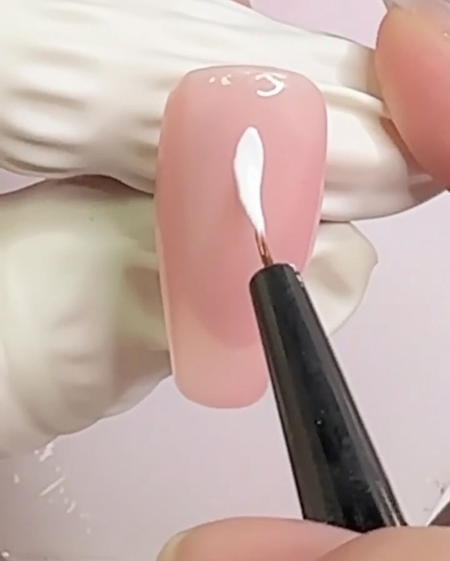 누드 톤의 손톱 중앙에 X자 형태로 교차하는 두 개의 화이트 라인.