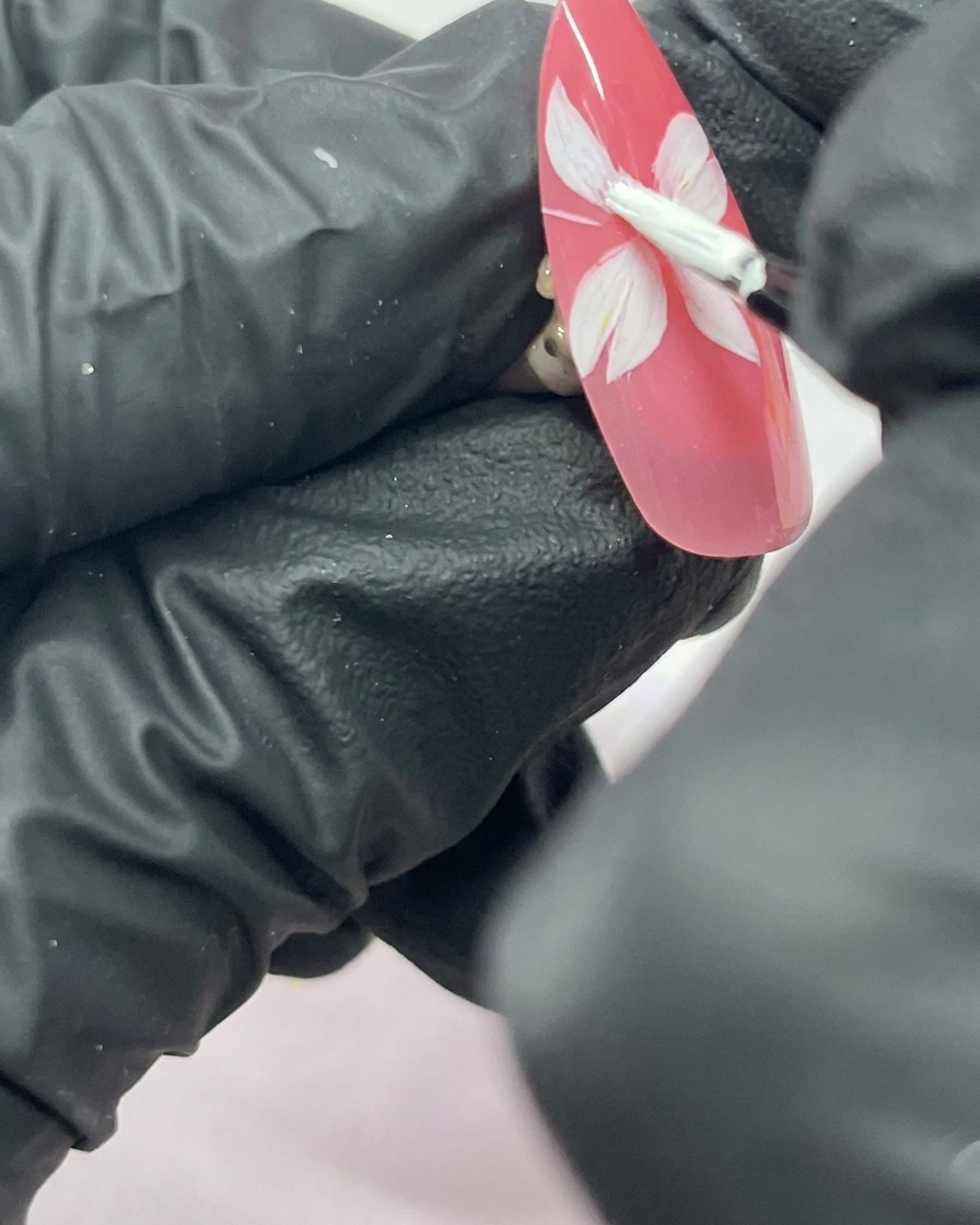 핑크빛 배경 위에 다섯 장의 잎을 가진 흰색 벚꽃이 완성된 네일아트.