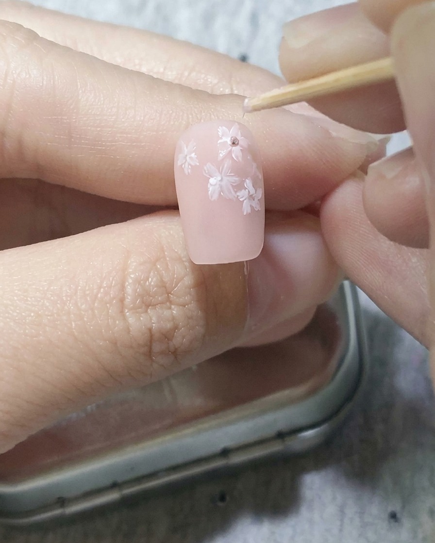 이쑤시개로 화이트 벚꽃 중심에 진한 핑크색 점을 찍는 모습.