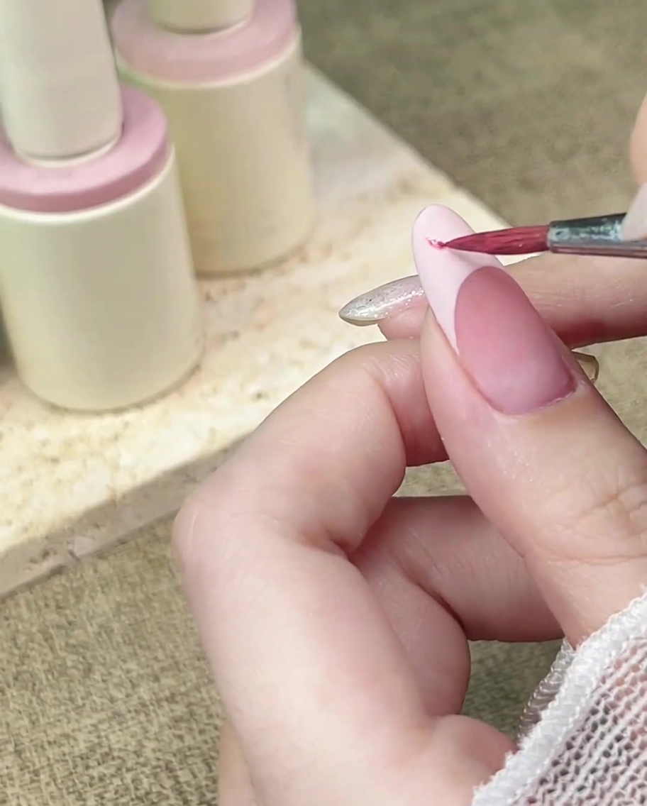 매트한 프렌치 팁 위에 세밀한 브러시로 핑크색 수채화 물감을 톡톡 찍어 바르는 모습