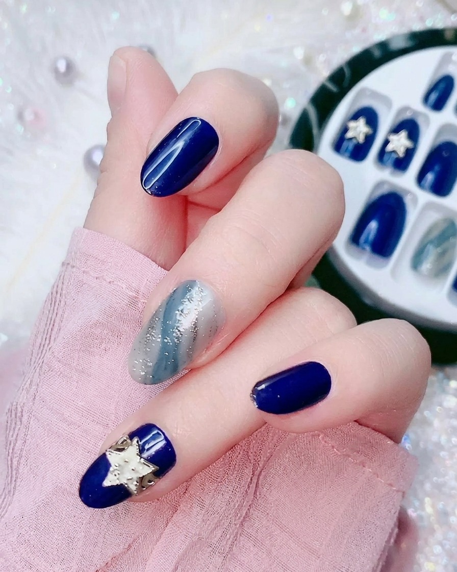 일렉트릭 블루 프레스온 네일 뒷면의 작은 투명 비닐 필름을 떼어내는 손가락 클로즈업 사진.
