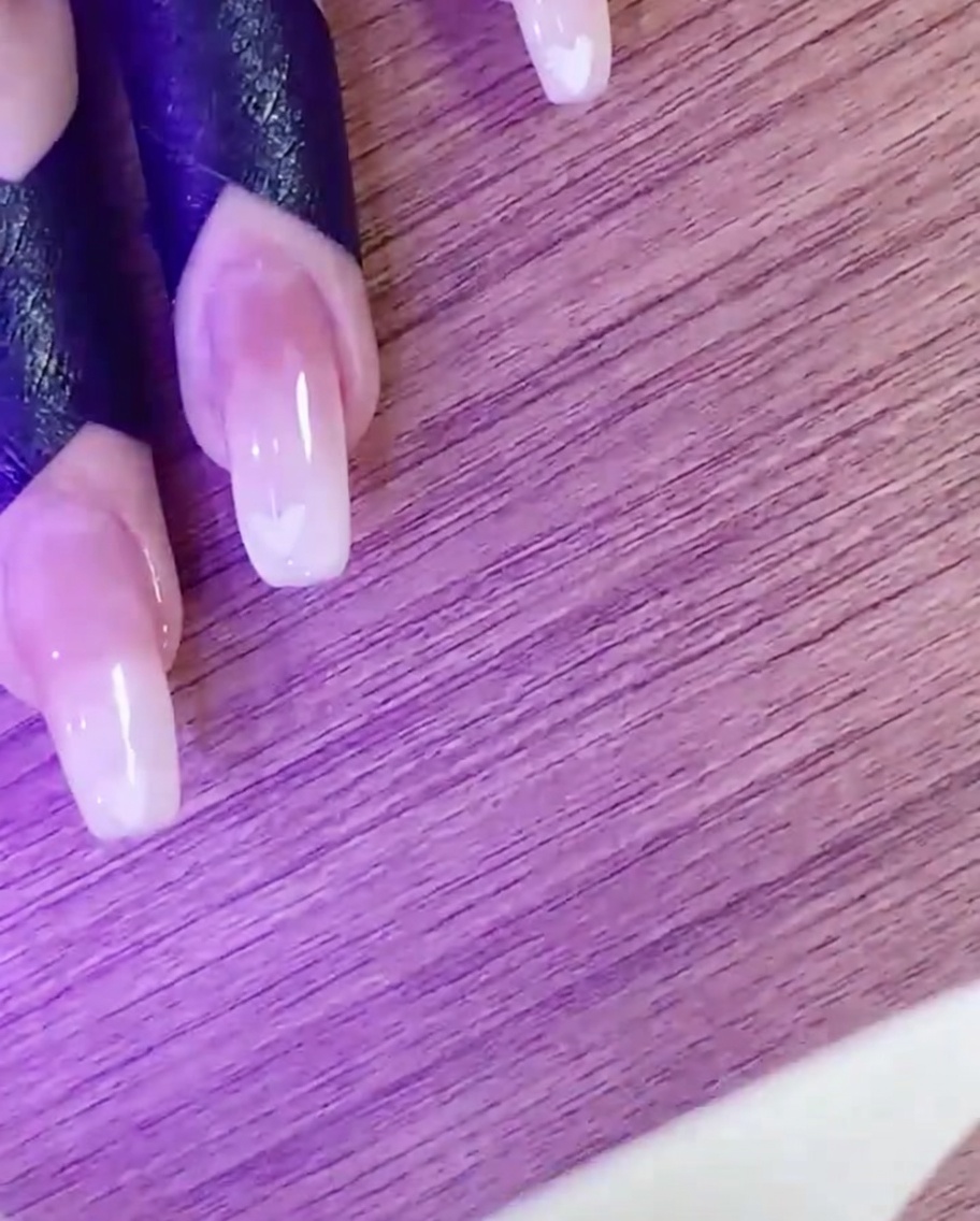 UV/LED 램프 아래에서 하트 네일 아트 디자인을 큐어링하는 손.