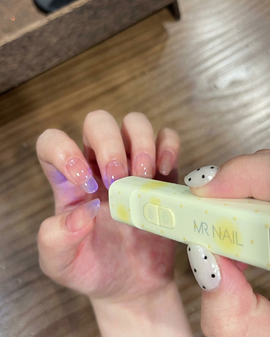 MR NAIL 브랜드의 휴대용 UV 램프 아래에 손가락을 넣어 젤을 굽는 모습.