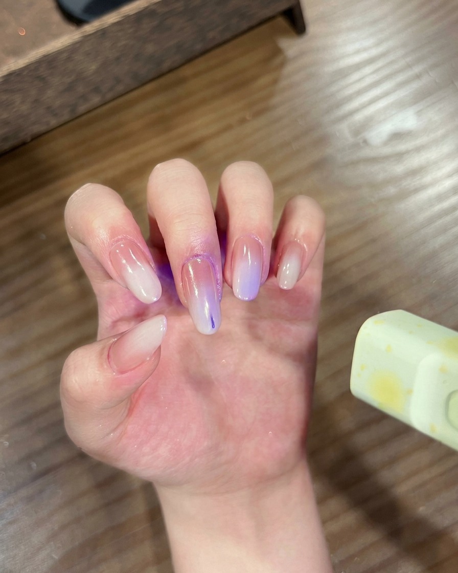 그라데이션 크롬 네일을 한 손이 큐어링을 위해 UV/LED 램프 안에 있는 모습.