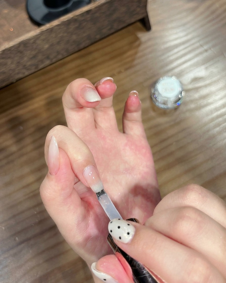 완성된 크롬 그라데이션 네일에 투명 탑 코트를 덧바르는 모습.