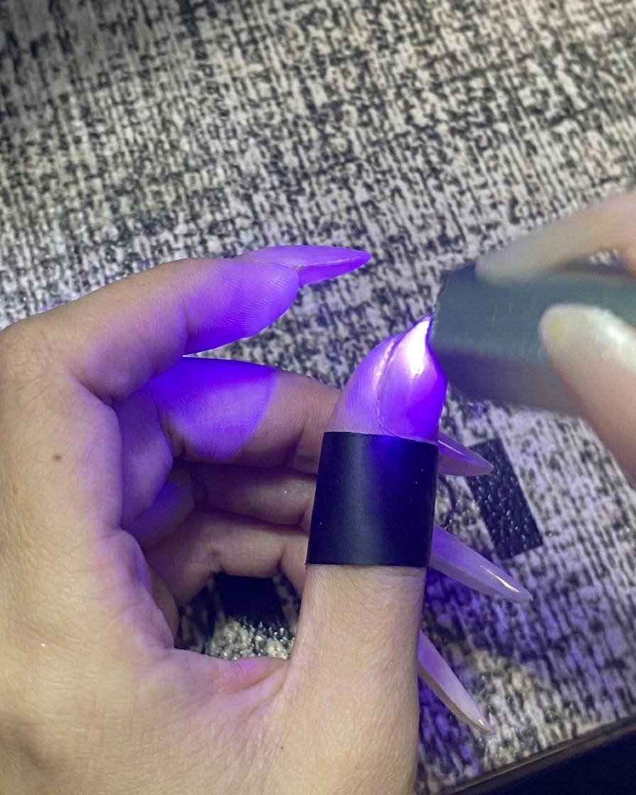 휴대용 UV/LED 젤 램프에 손가락을 넣고 빛을 쪼이는 모습.