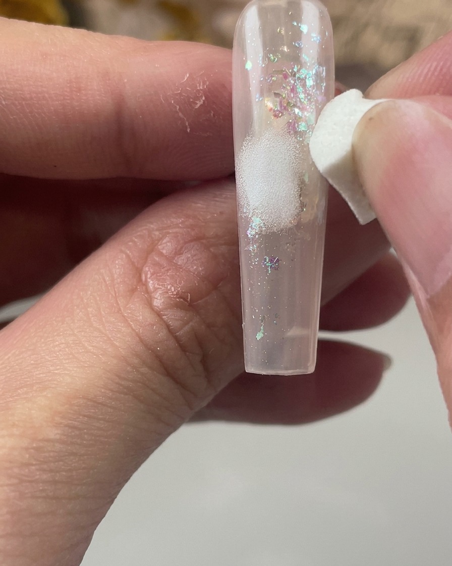 글리터가 덮인 네일 중앙에 하얀색 화장용 스펀지로 화이트 물감을 부드럽게 두드려 바르는 모습.