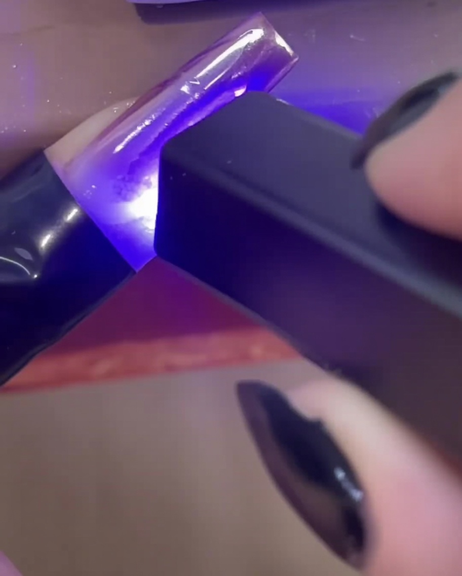 미니 핸디형 UV/LED 램프로 손톱 위 3D 빌더 젤 라인을 큐어링하는 모습.