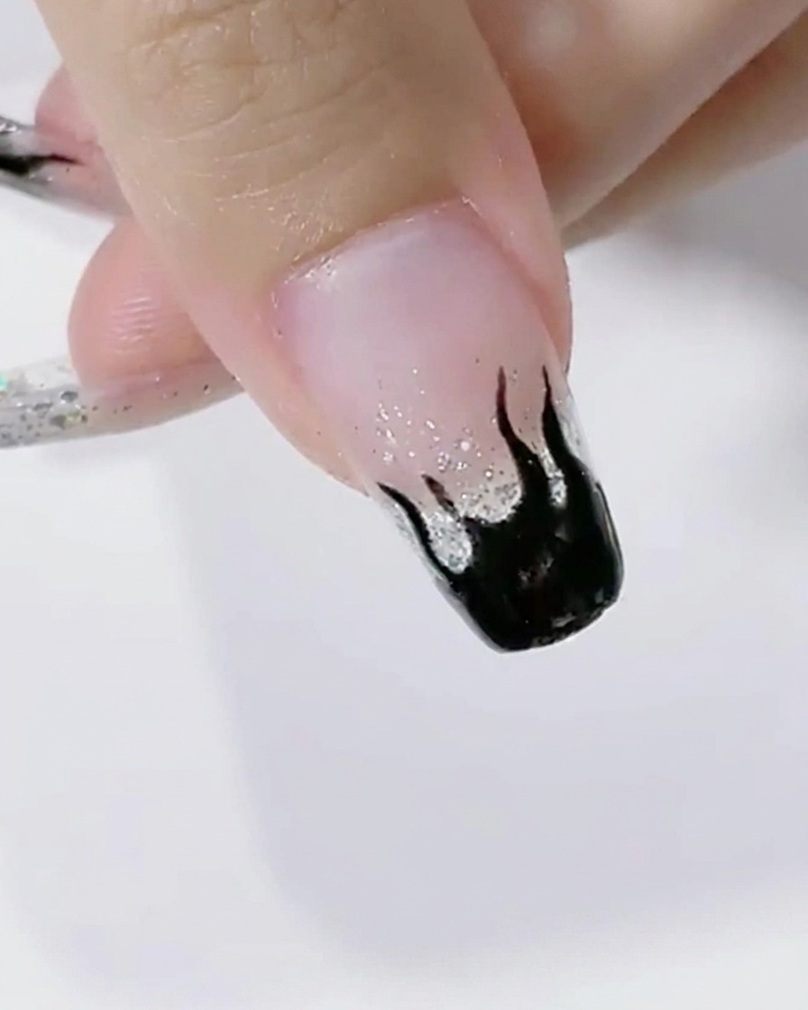 블랙 플레임 아트가 완성된 네일이 LED 램프 속에서 큐어링되는 모습.
