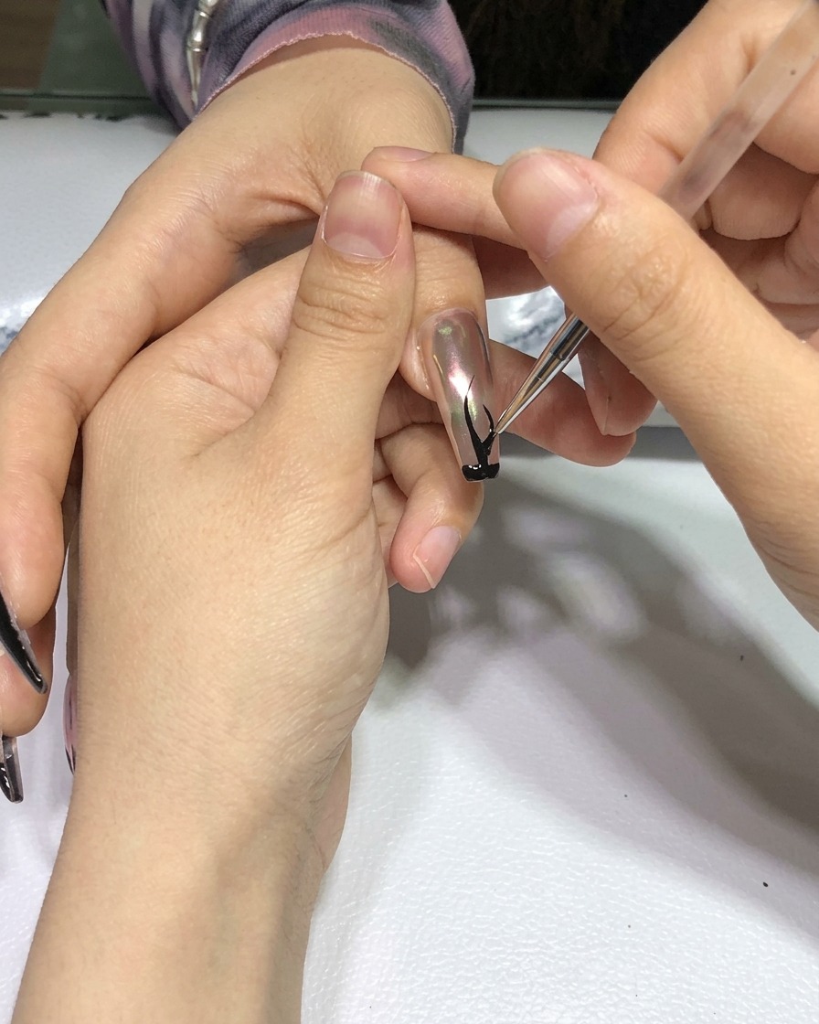 블랙 불꽃 아트가 완성된 손을 전문가용 네일 램프 안에 넣고 단단하게 굽는 모습.