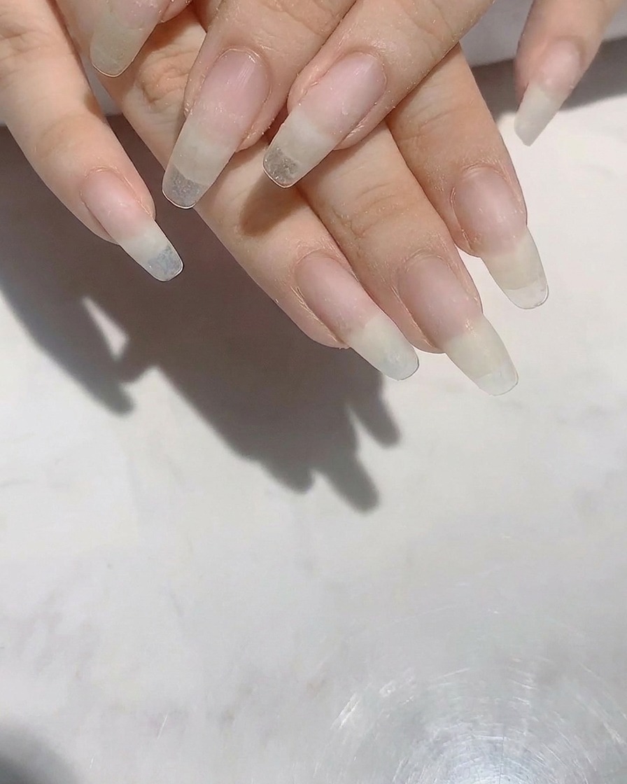 네일 파일을 사용하여 긴 자연 손톱의 형태를 다듬는 모습.