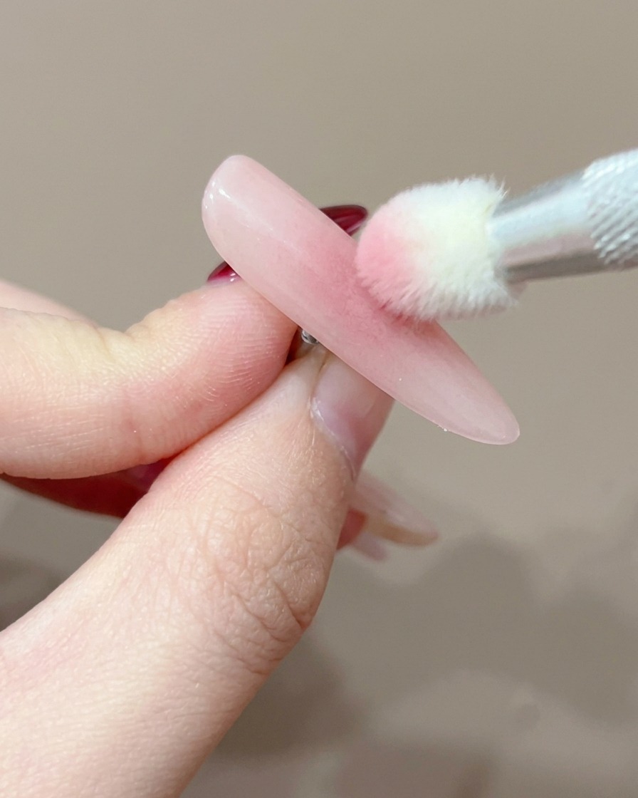 큐어링을 위해 UV 램프 아래에 위치한 네일 팁의 클로즈업 이미지.