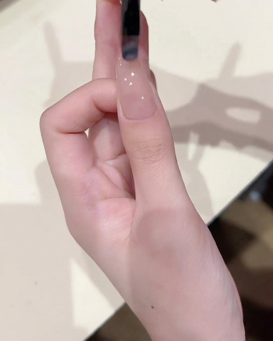베이스 층이 발린 손톱 위에 시어 누드 젤을 얇고 고르게 펴 바르는 브러쉬 모습.