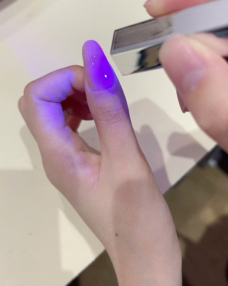 큐어링된 젤 네일 표면을 리무버가 묻은 솜으로 닦아내는 모습.
