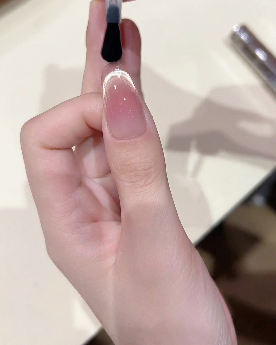 완성된 캣아이 네일 위에 반짝이는 탑 코트를 얇게 펴 바르는 모습.