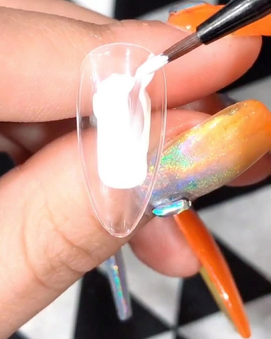 흰색 꽃잎 아트가 그려진 투명 네일 팁을 UV/LED 네일 램프 안에서 경화하는 모습.