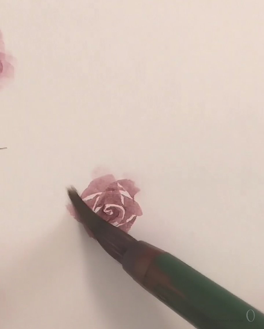 작은 붓으로 섬세한 핑크색 수채화 물감을 사용하여 장미의 마지막 바깥쪽 꽃잎을 그리는 모습.