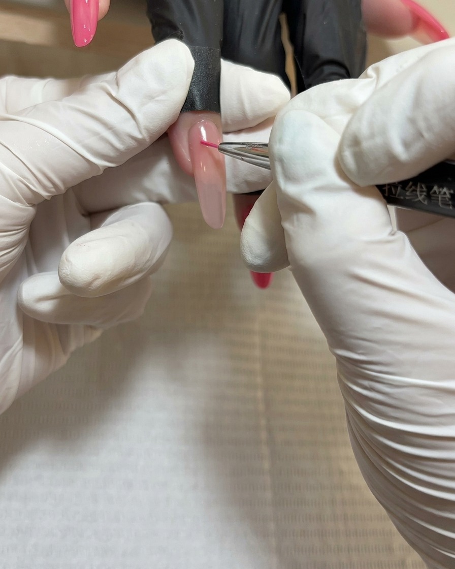 라이너 브러시로 세 번째 장미 꽃잎 뭉치 중심부에 짙은 빨간색 젤을 바르는 모습의 근접 촬영.