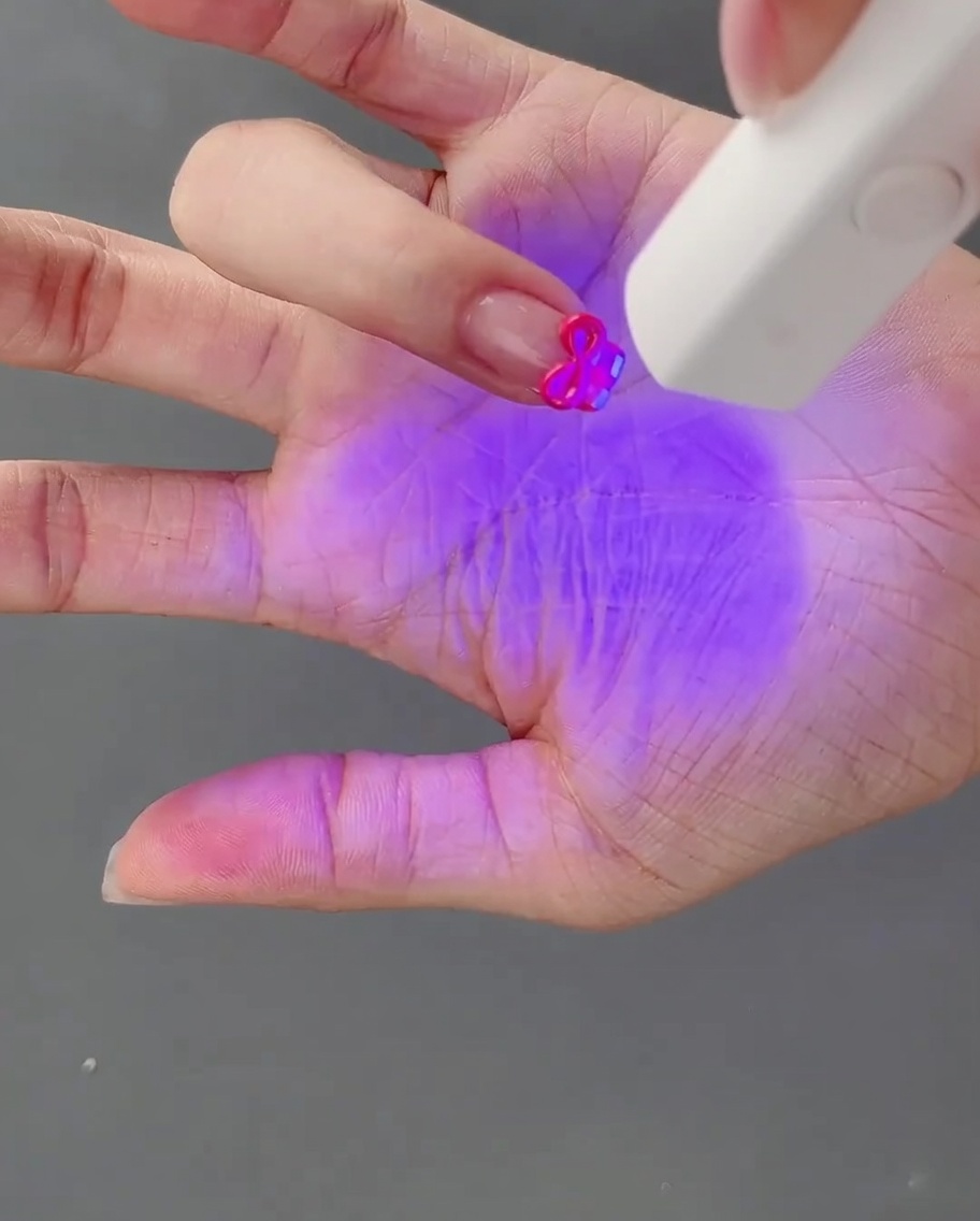 완성된 3D 젤 리본을 올린 손을 UV 네일 램프 아래에서 큐어링하는 모습.