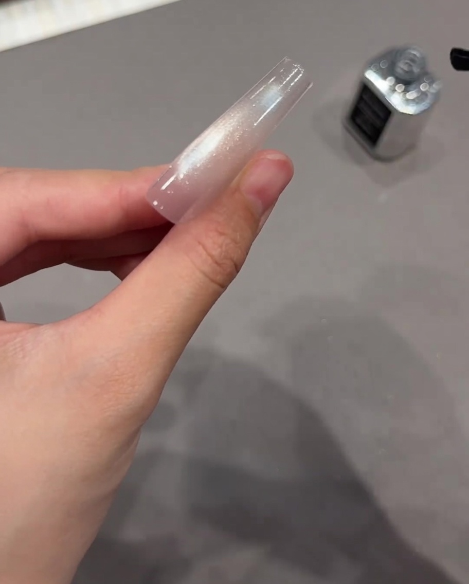 반짝이는 자석 젤 위에 탑 코트를 덧바르는 모습.