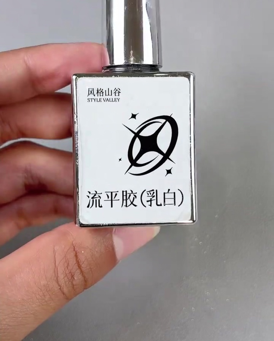 작은 브러시를 사용하여 장식된 네일의 모서리에 밀키 화이트 젤을 한 방울 올리는 모습.