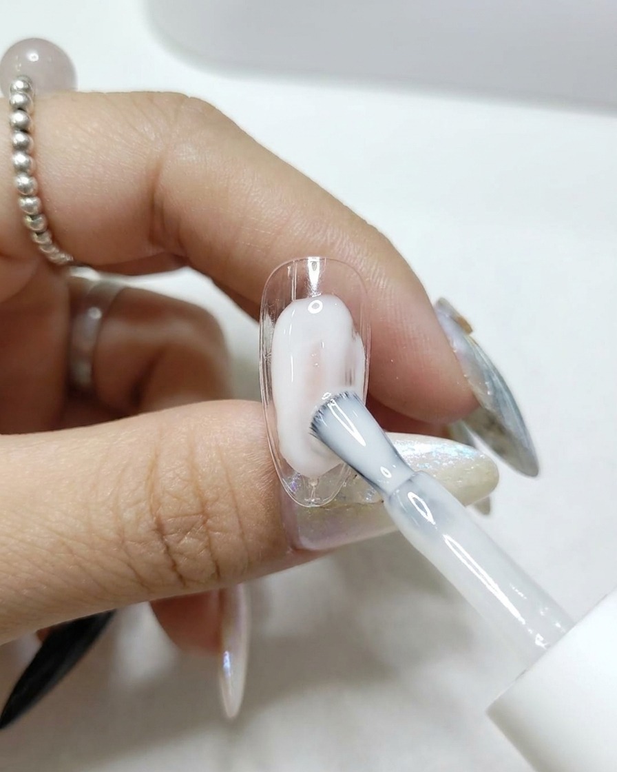 투명한 네일 팁에 투명하고 윤기 나는 탑코트를 바르는 브러시.