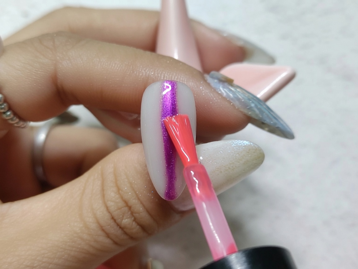 메탈릭하게 마무리된 손톱 중앙에 굵은 레드 수채화 잉크를 세로로 바르는 네일 아트 브러시.
