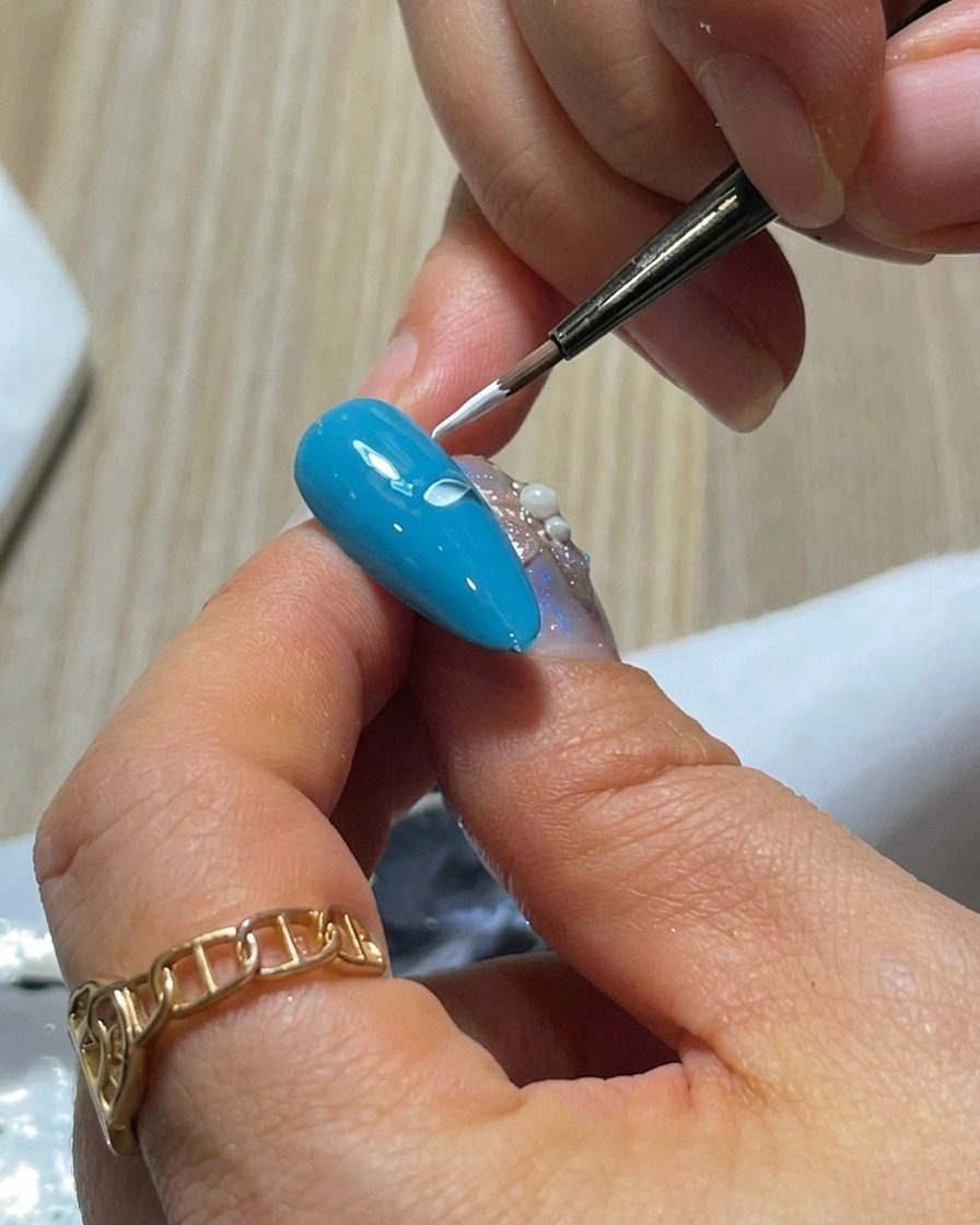 블루 네일 위에 프레스 앤 리프트 기법으로 나란히 두 개의 화이트 꽃잎을 그린 모습.