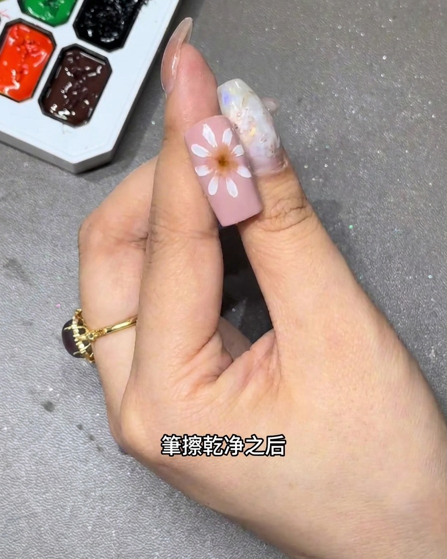 핑크 네일 베이스 위에서 화이트 꽃잎을 블렌딩하여 부드러운 그라데이션을 만드는 모습의 클로즈업.