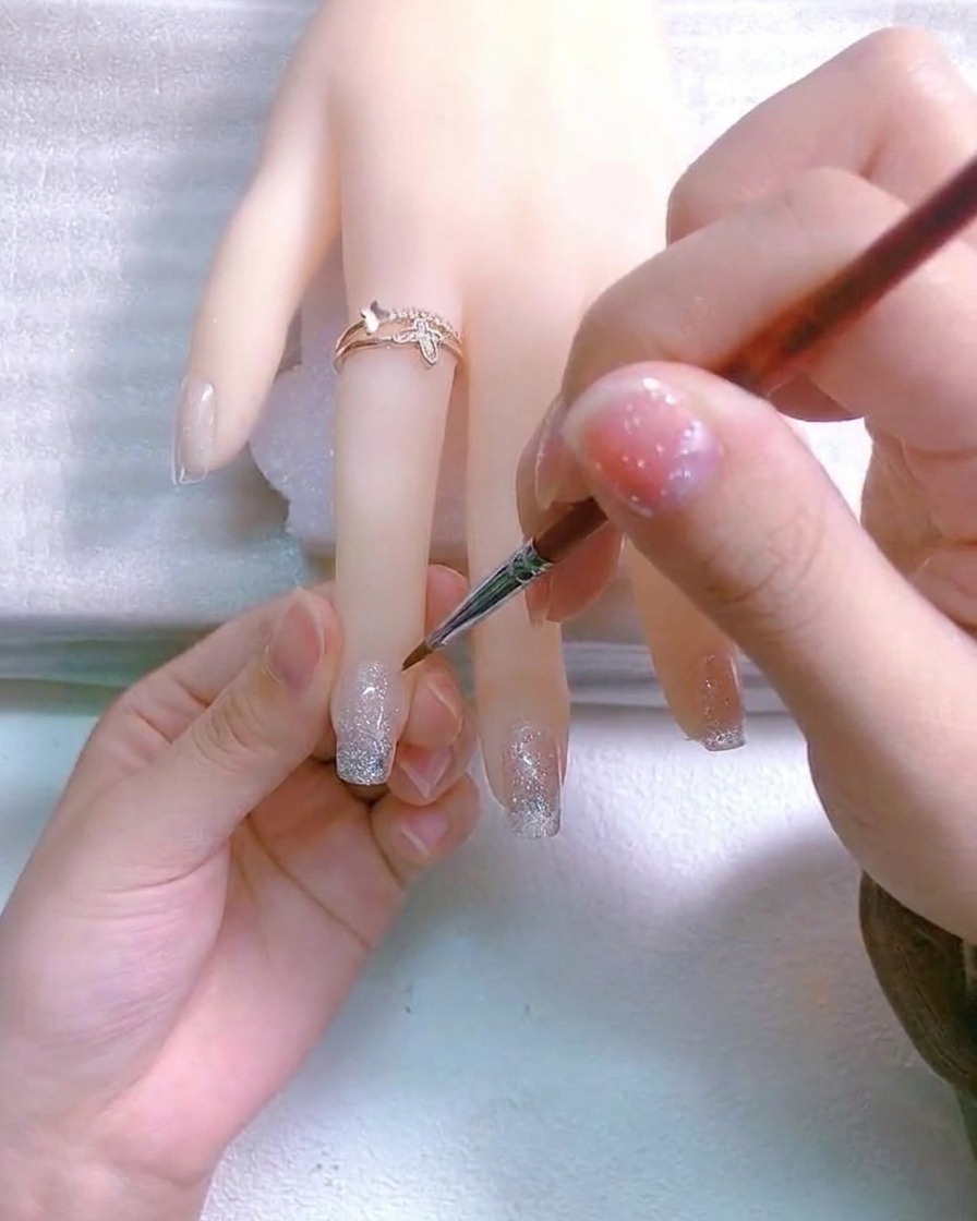 세밀한 브러시로 손톱 위에 작은 흰색 십자 모양을 그린 모습.