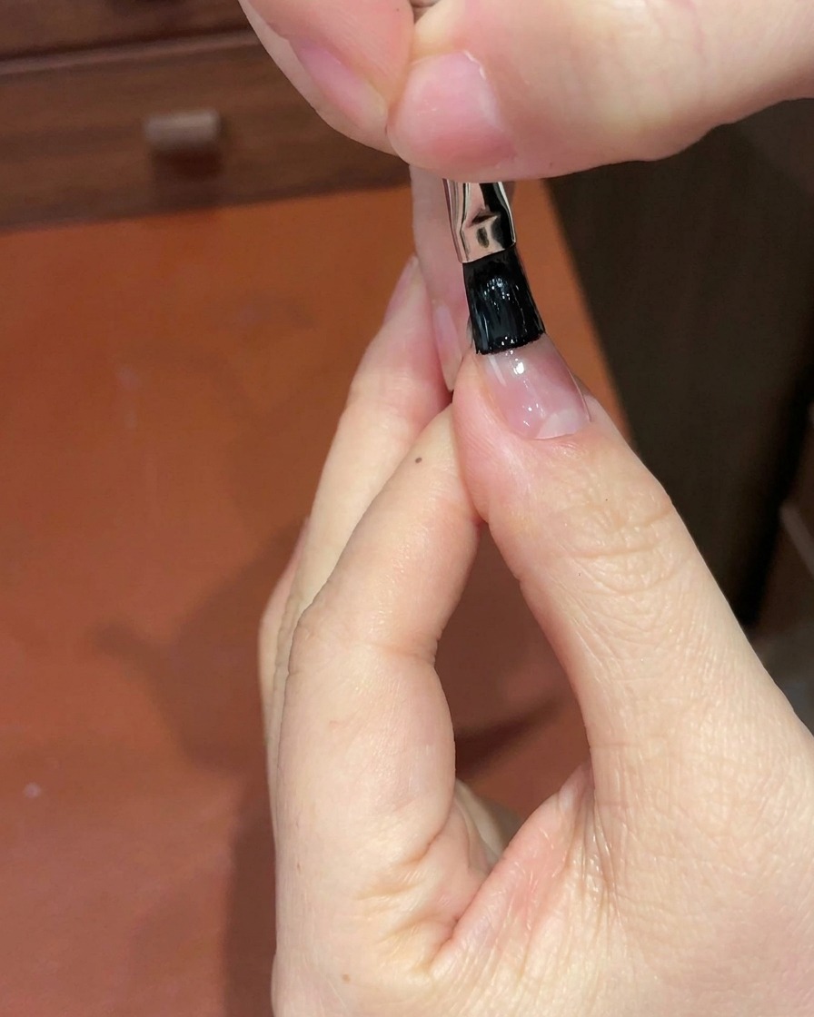 디테일 브러시를 사용하여 손톱 끝부분에 블랙 젤을 바르는 모습.