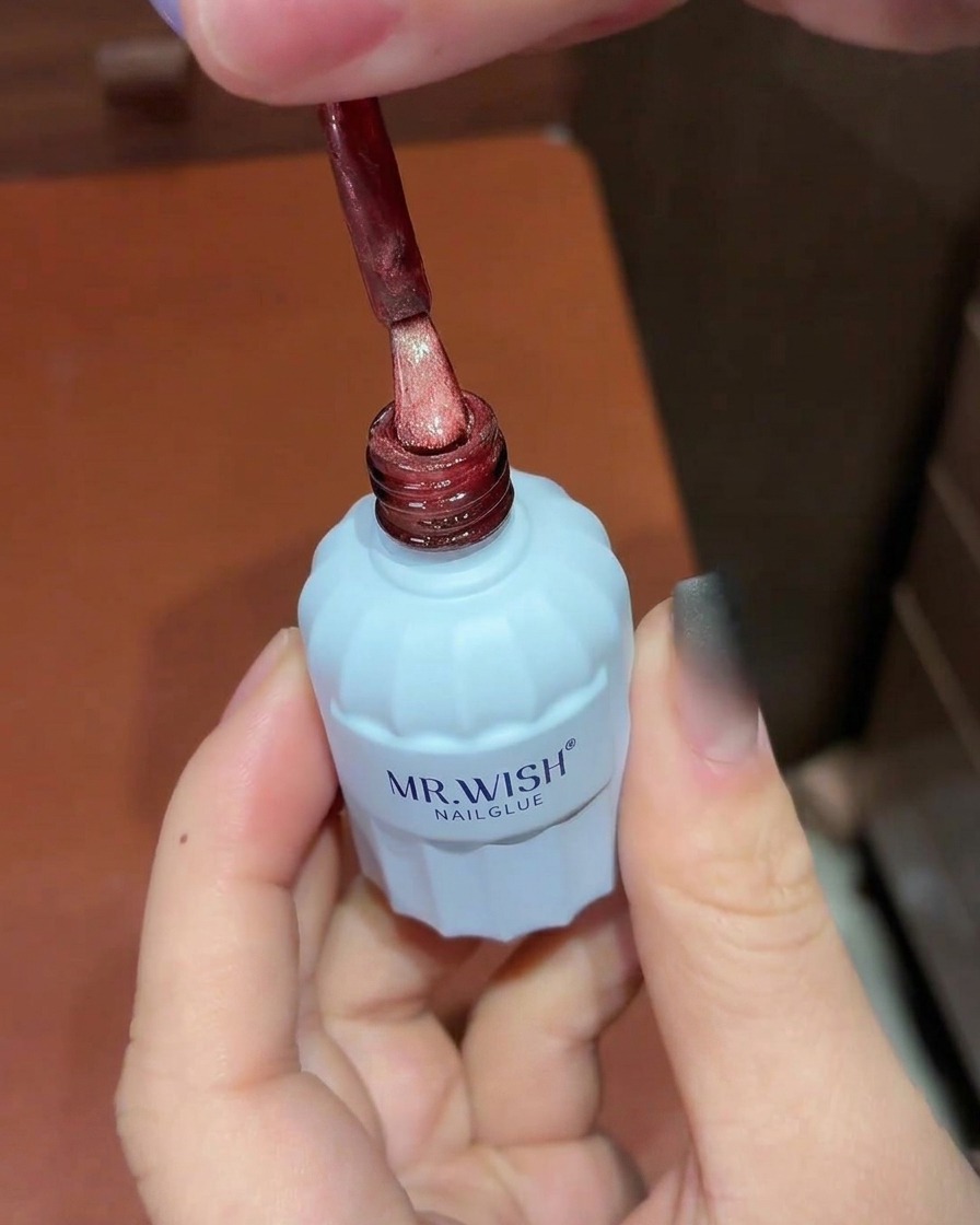 경화된 블랙 옴브레 베이스 위에 레드 펄 캣아이 젤 폴리시를 브러시로 바르는 모습.