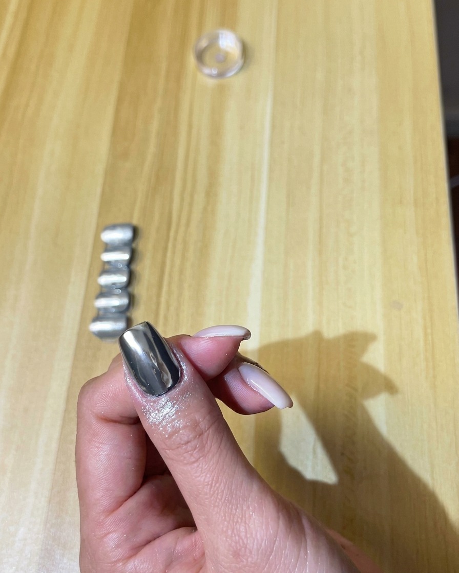 부드러운 메이크업 브러시로 손톱 위의 남은 실버 크롬 파우더를 털어내는 모습.